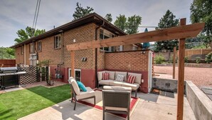 A backyard with a patio area, a barbecue grill, and a wooden pergola.