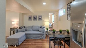 A compact living space with a sofa, a dining table with chairs, a refrigerator, and a small kitchen area.
