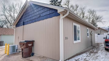 A single-story building with a beige exterior and a dark blue roof. It has a small window and a door, with a number '315' displayed on the wall.