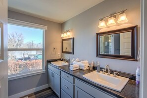 A bathroom with two sinks, a large mirror, and a window providing a view of the outside. - 2BR Modern & Chic Comfy Home in Old Colorado (Colorado Springs)