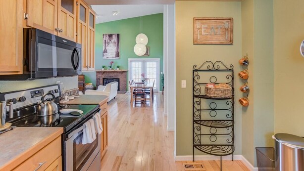 A kitchen with wooden cabinets, a microwave, stove, and a dining area with a table and chairs. - 4BR Garden of the Gods Family Getaway (Colorado Springs)