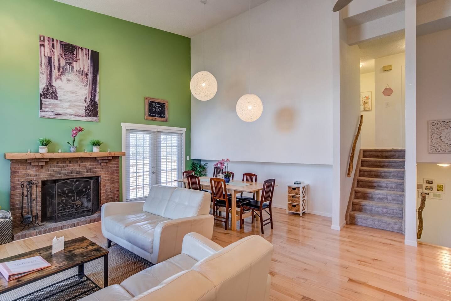 Una sala de estar con chimenea, una zona de comedor y una escalera.