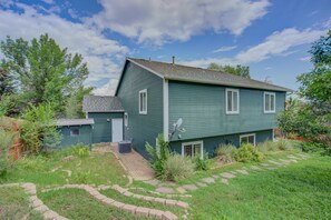 A green two-story house with a sloped roof, a satellite dish, and a small attached garage. - 4BR Garden of the Gods Family Getaway (Colorado Springs)