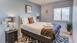 A bedroom with a bed, bedside lamps, a nightstand, a window, and a plant. - 4BR Garden of the Gods Family Getaway (Colorado Springs)