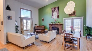 A living room with a fireplace, a piano, and a dining area with a table and chairs. - 4BR Garden of the Gods Family Getaway (Colorado Springs)