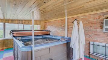 A hot tub area with a brick wall, wooden ceiling, and a window.