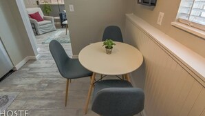 A dining area with a round table and four grey chairs, a small potted plant on the table, and a clock on the wall. - 2BR Garden-level Great Outdoors Dog Friendly (Colorado Springs)