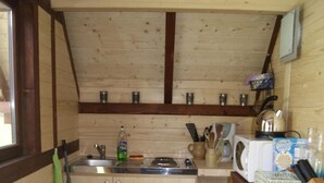 A compact kitchen with wooden walls, a built-in sink, and a microwave. - Moulin de Lachaud (Sainte-Fortunade)