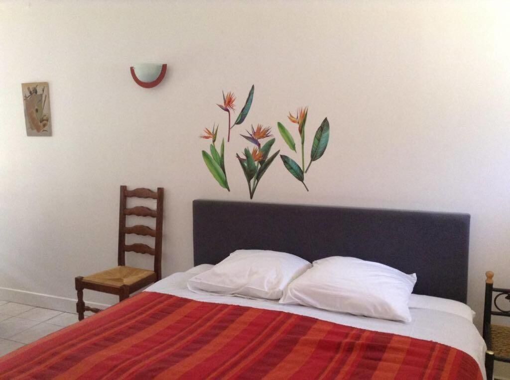 A bedroom with a bed, a chair, and a wall decoration.