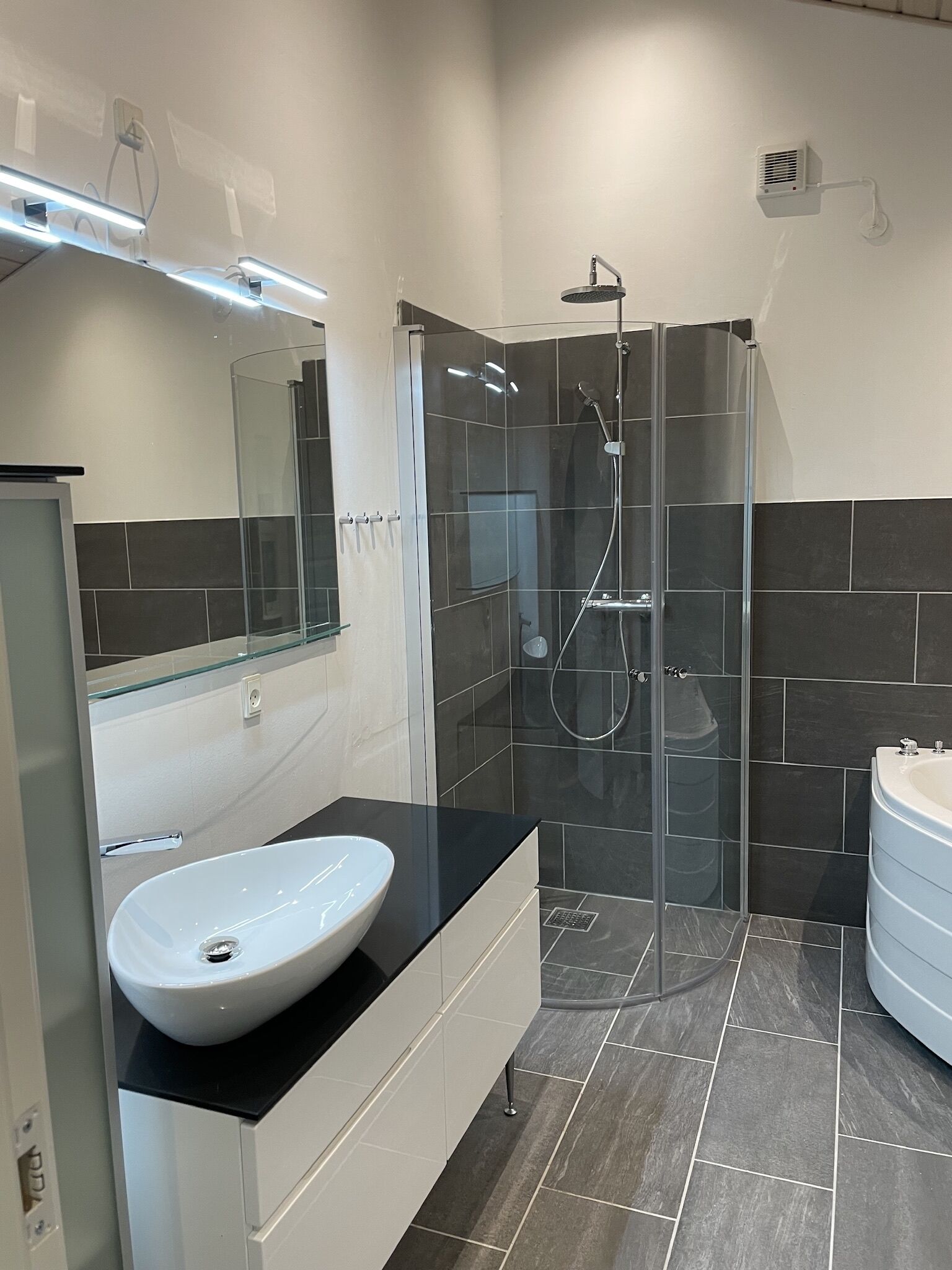 A modern bathroom with a glass-enclosed shower, a white sink, and a bathtub.