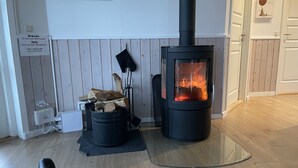 A room with a wood-burning stove, a black trash bin, and a wooden floor. - Beautiful holiday home on Nordals, Vinkelbæk 40 (Nordborg)