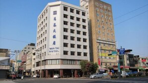 Un hôtel au design moderne, reconnaissable à son grand panneau indiquant « WANTAI HOTEL ».