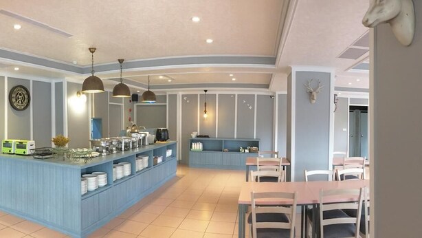 Un espace repas moderne avec un comptoir bleu, des chaises blanches et des luminaires suspendus.