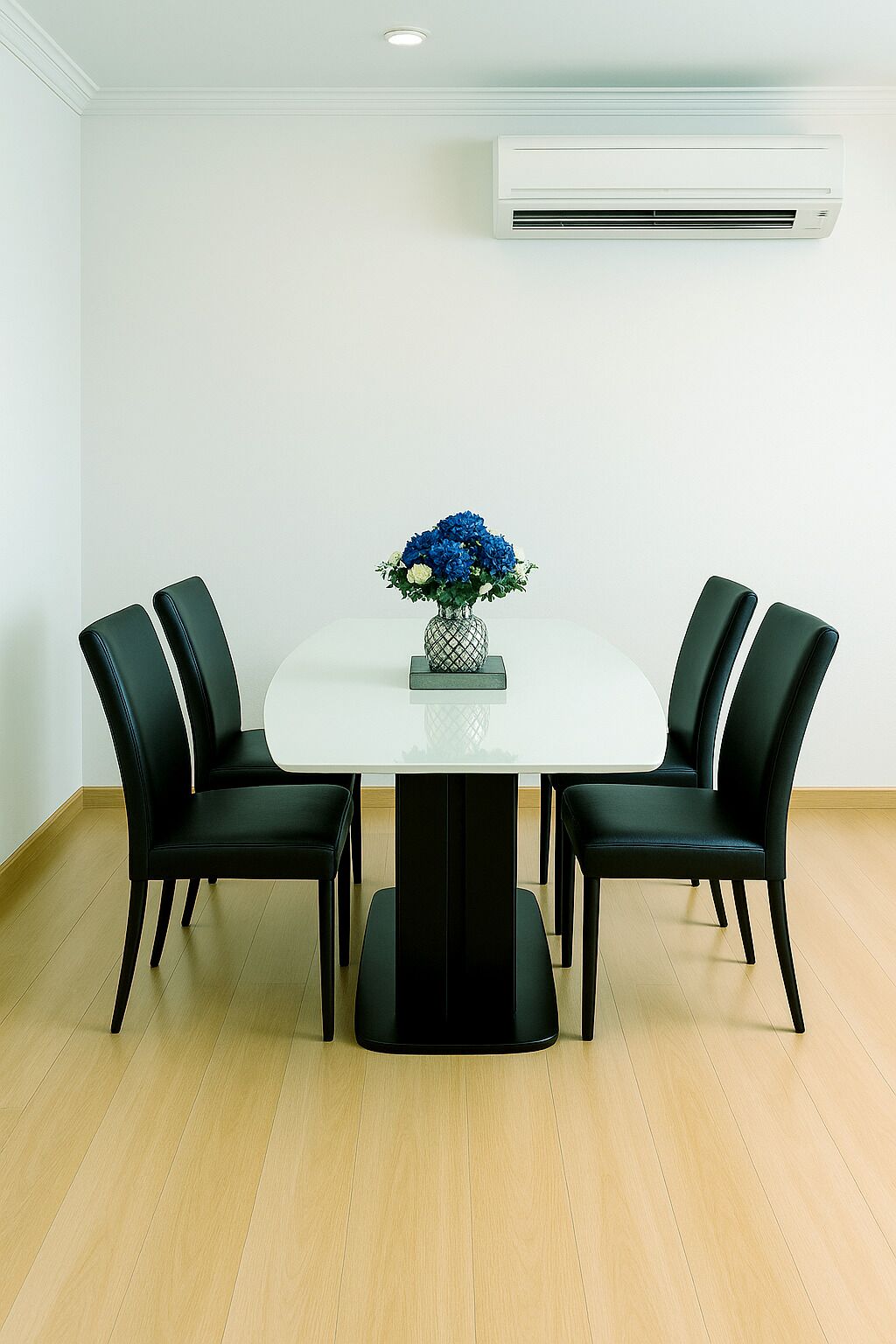A conference room with a white table, four black chairs, and a vase with blue flowers.