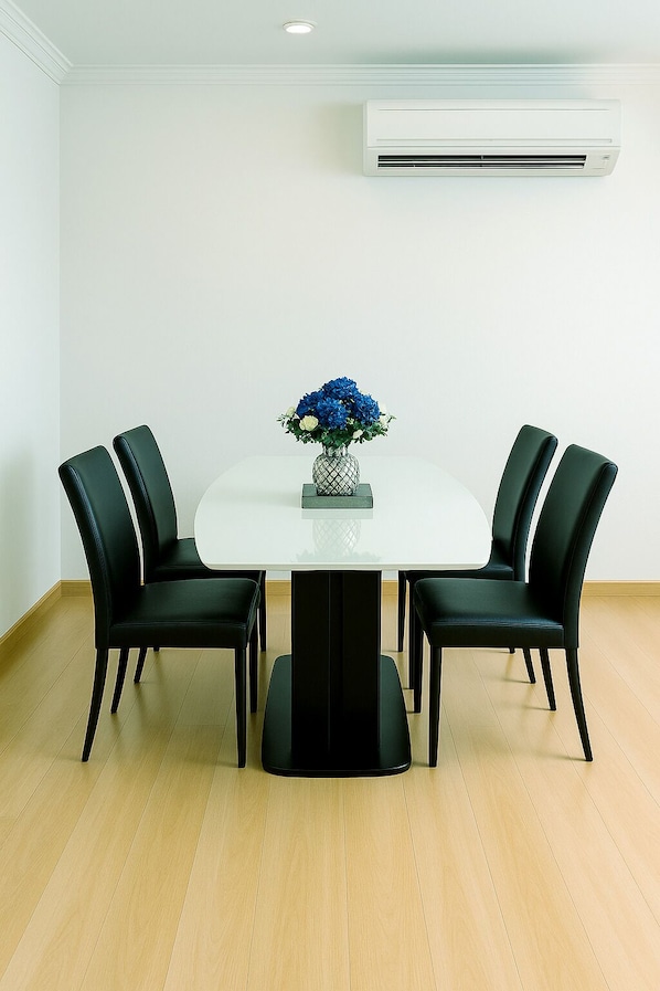 A conference room with a white table, four black chairs, and a vase with blue flowers. - Pacific Residence 39 (Bangkok)