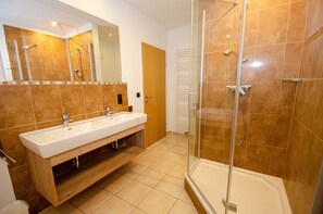 A bathroom with a double sink, a glass-enclosed shower, and a wooden vanity.