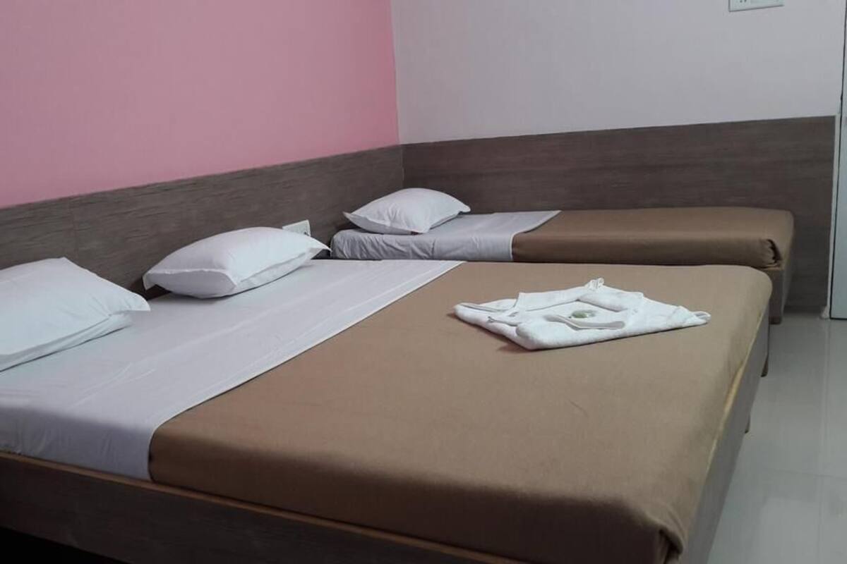 Quarto de hotel com duas camas, cada uma com almofadas brancas e colchas castanhas. Uma toalha dobrada está colocada na cama em primeiro plano.