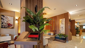 A modern hotel lobby with a reception desk, seating area, and decorative plants. - Frt Airlines Hotel - Istanbul Airport (Arnavutköy)