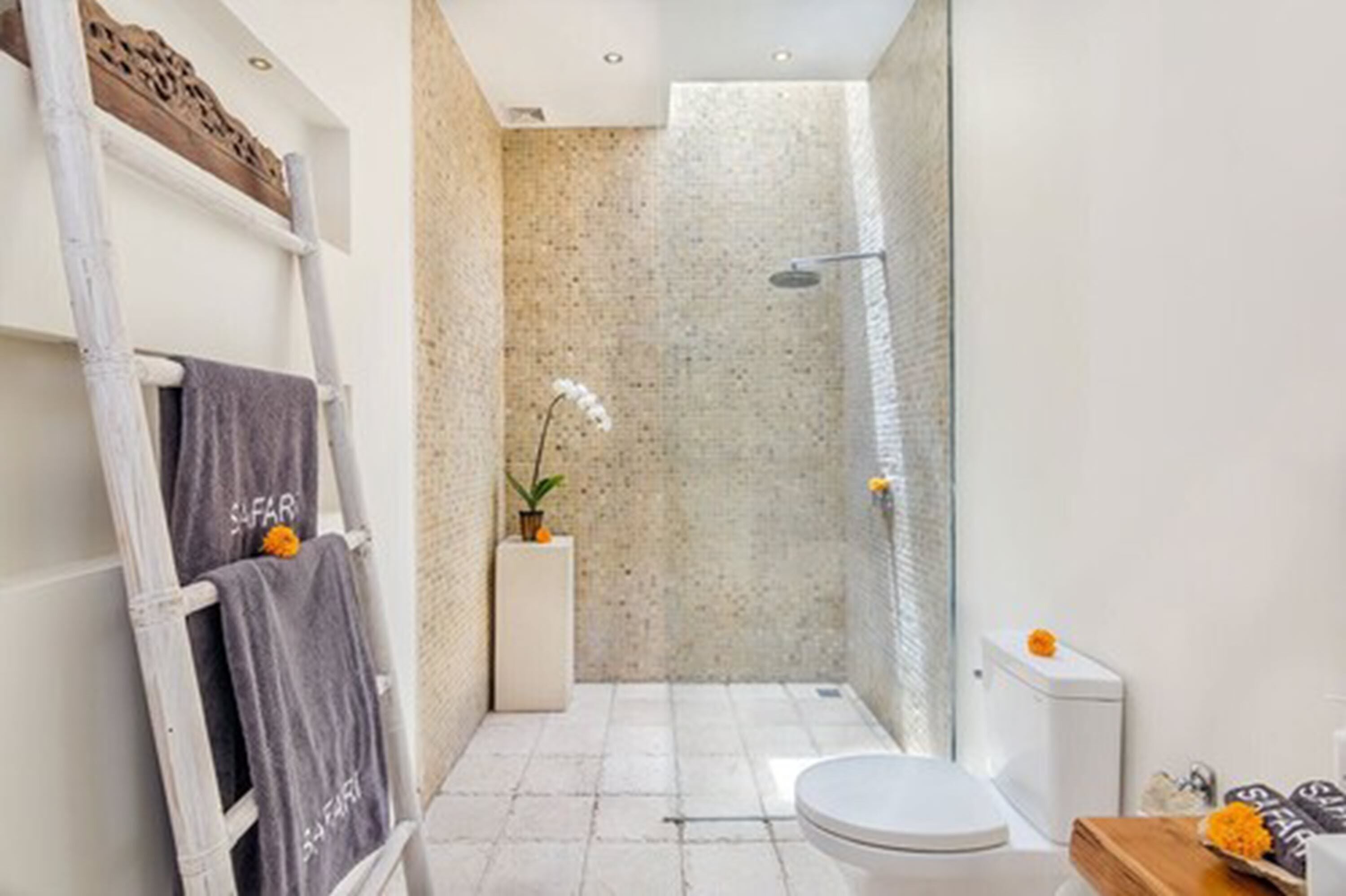 A compact bathroom with a shower, toilet, and a towel rack with towels.