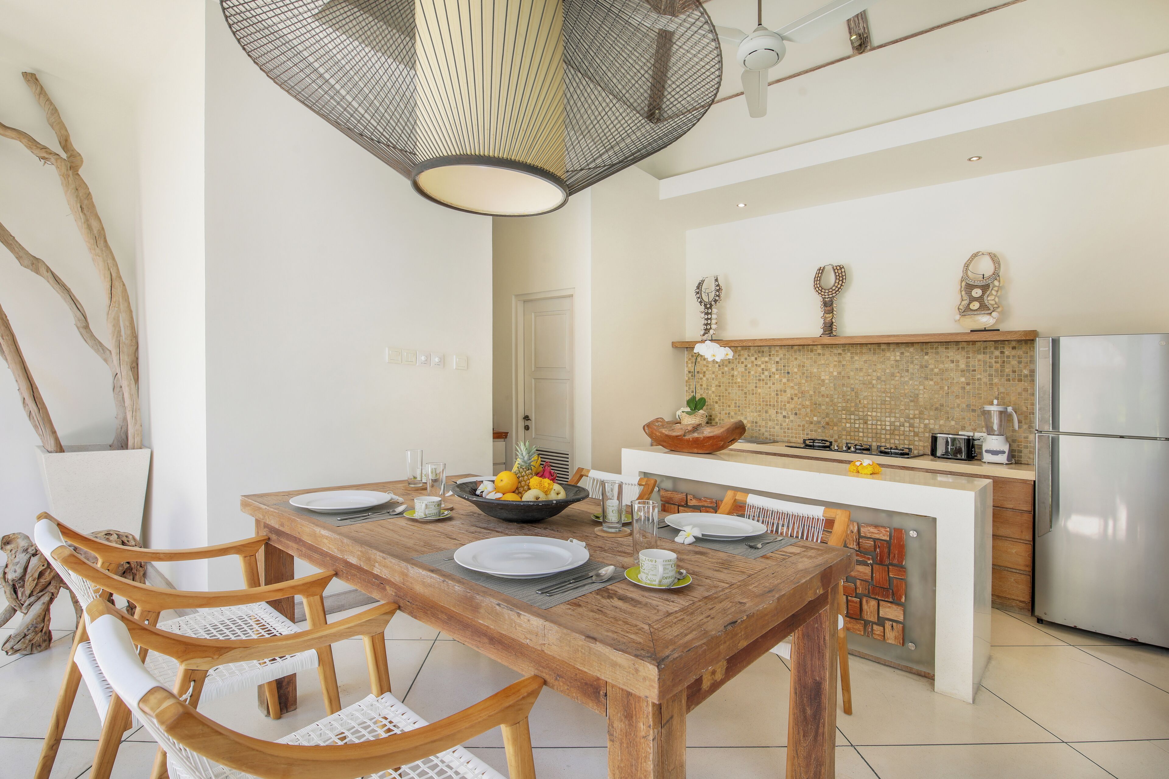 A modern kitchen with a central island, white cabinetry, and a hanging light fixture.