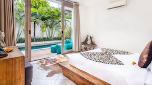 Une chambre dotée d’un grand lit, d’un banc en bois, d’un bureau et offrant une vue sur une piscine et un espace verdoyant.