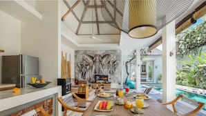 Un coin repas avec vue sur la piscine, un réfrigérateur et une fresque représentant des éléphants.