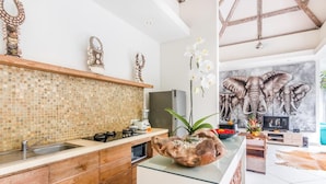 Une cuisine moderne avec un mur recouvert de mosaïques, des armoires en bois et un îlot central agrémenté d’un saladier décoratif.