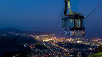 A cable car with "TENGDU" written on it, suspended over a cityscape at night.