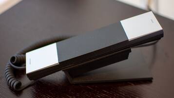A black telephone on a dark wooden table.