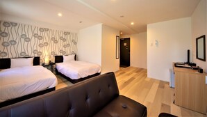 Habitación de hotel con dos camas, un sofá, un escritorio y una pared con estampado floral.