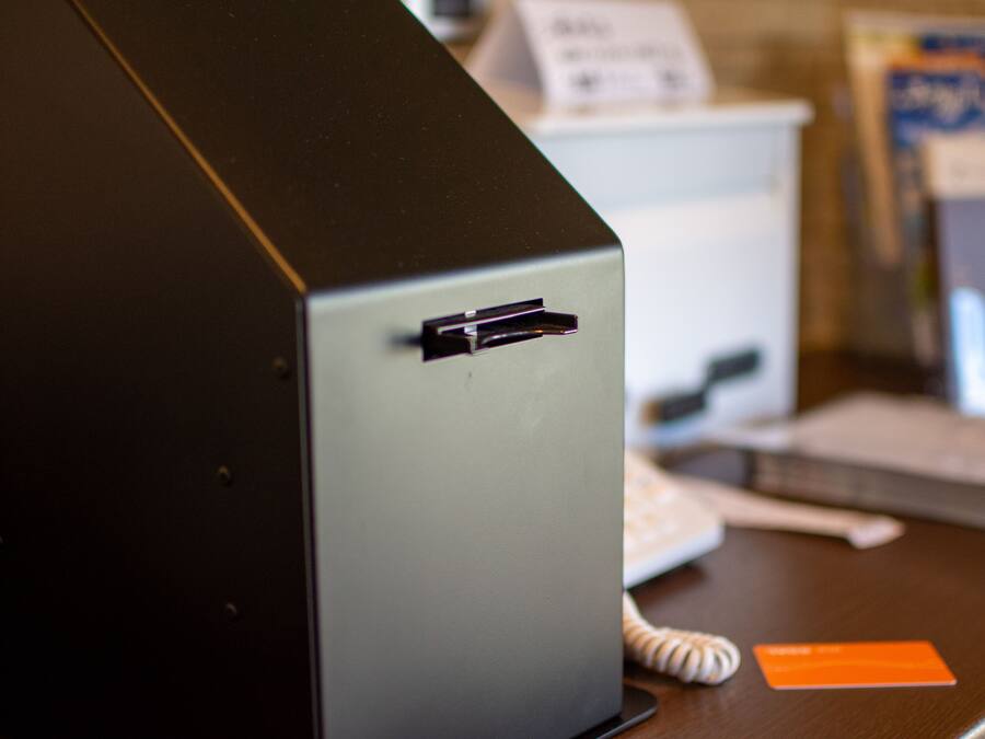 A close-up of a computer monitor with a USB port, a card reader, and a telephone on a desk.