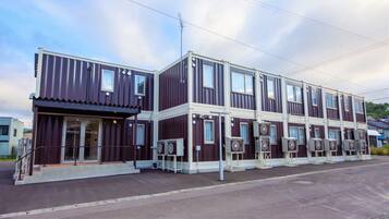 A multi-story building with a dark facade, large windows, and multiple air conditioning units.