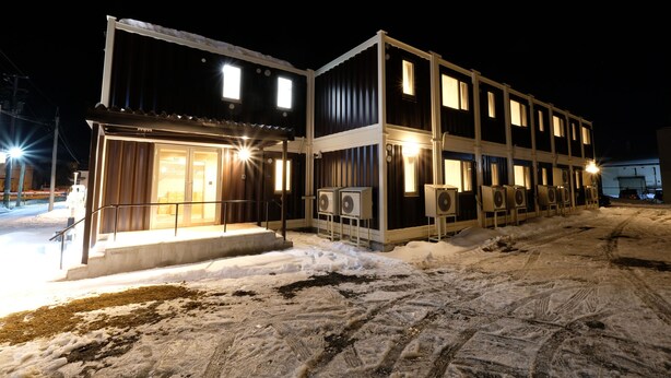 Un edificio de dos pisos con varias ventanas y suelo cubierto de nieve.