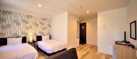 A hotel room with two beds, a sofa, a desk, and a wardrobe.