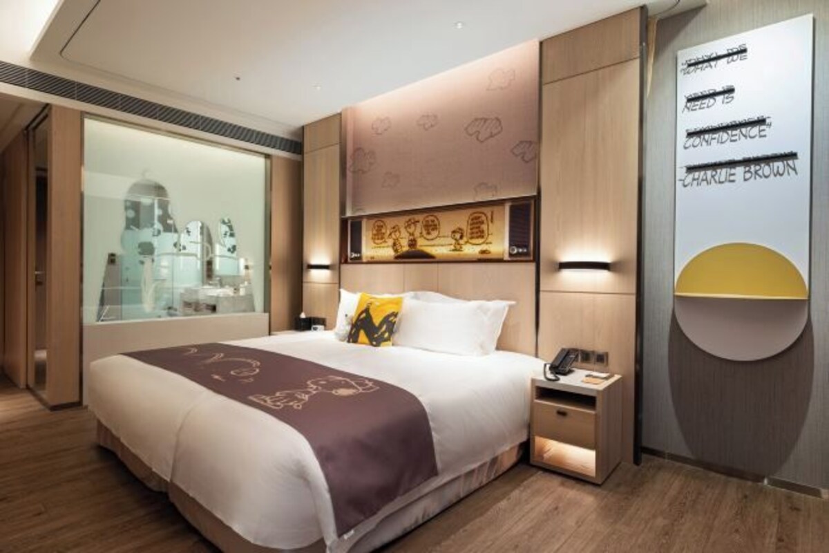 A modern hotel room with a large bed, bedside tables, a mirror, and a wall with motivational quotes.