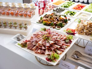 Un bufé con diversas opciones de comida, incluyendo carnes, ensaladas y postres.