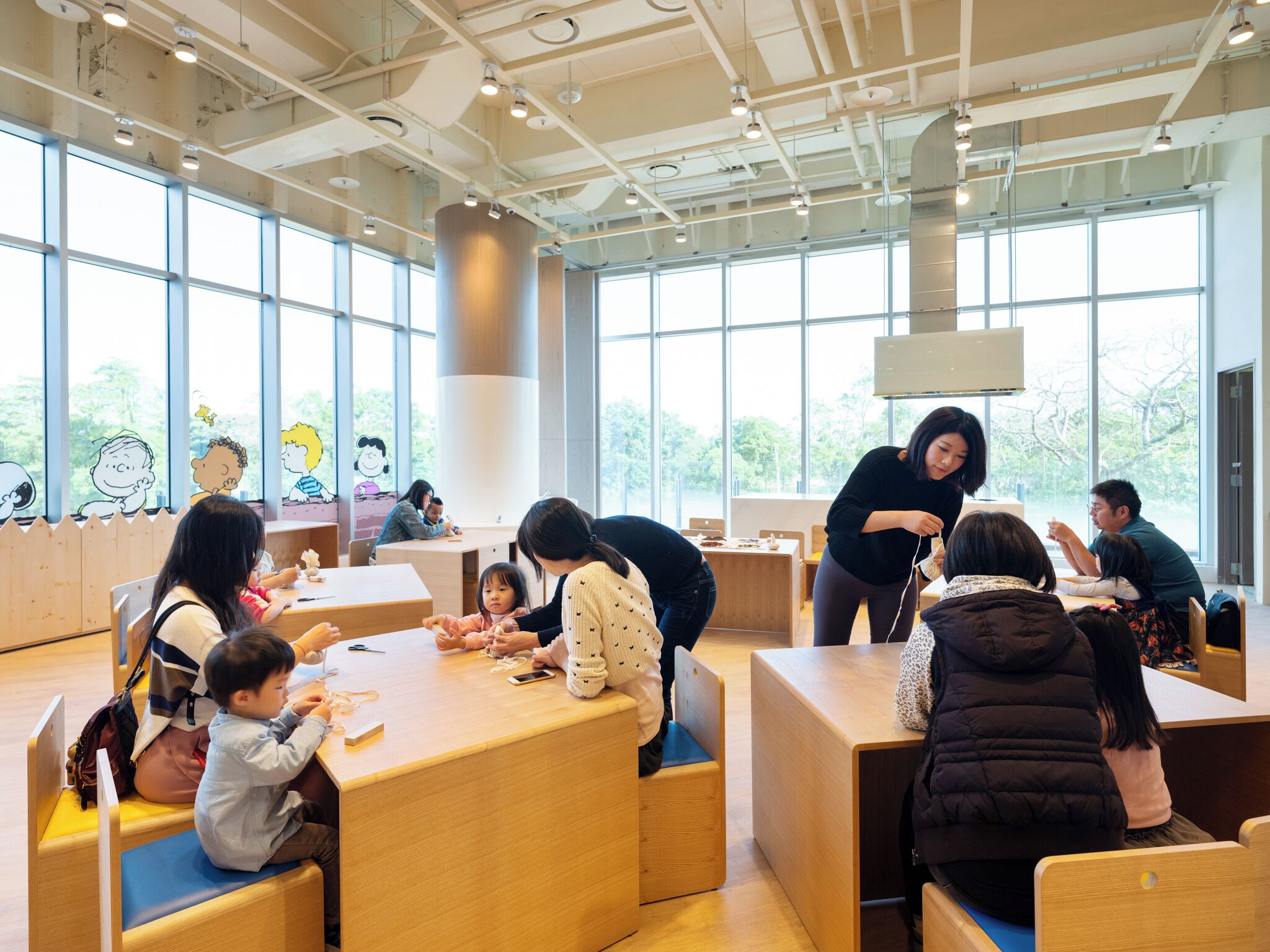 A modern indoor space with large windows, wooden furniture, and a clean, organized layout.