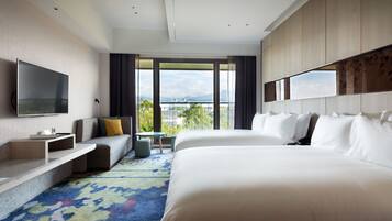 A modern hotel room with a large bed, a sofa, a TV, and a balcony with a city view.
