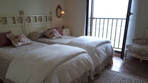 Un dormitorio con dos camas, una mesita de noche, una lámpara y una silla.