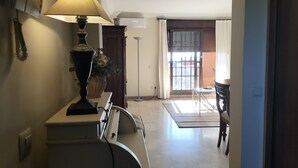 Un pasillo con una lámpara, una planta en maceta, una puerta y vistas a un balcón.