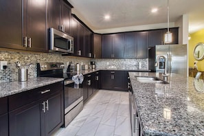 A modern kitchen with dark cabinetry, stainless appliances, and a granite countertop.