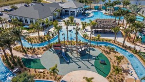 Un resort con múltiples piscinas, una zona de juegos para niños y un edificio con techo gris.