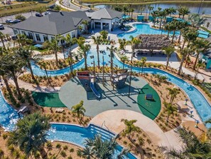 A resort with multiple swimming pools, a children's play area, and a building with a grey roof. - Spacious Storey Lake Home: Walk to Resort, BBQ, Game Room & Free WiFi! (Kissimmee)