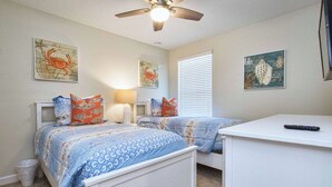 Un dormitorio con dos camas, un ventilador de techo y obras de arte en las paredes.