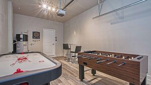 Una habitación con mesa de futbolín, mesa de billar y dardos.