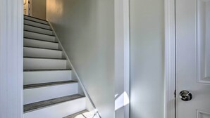 Uma escadaria com degraus de madeira e uma porta branca com maçaneta de prata.