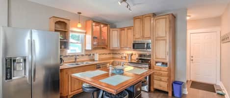 Una cocina moderna con electrodomésticos de acero inoxidable, armarios de madera y una isla central con taburetes.