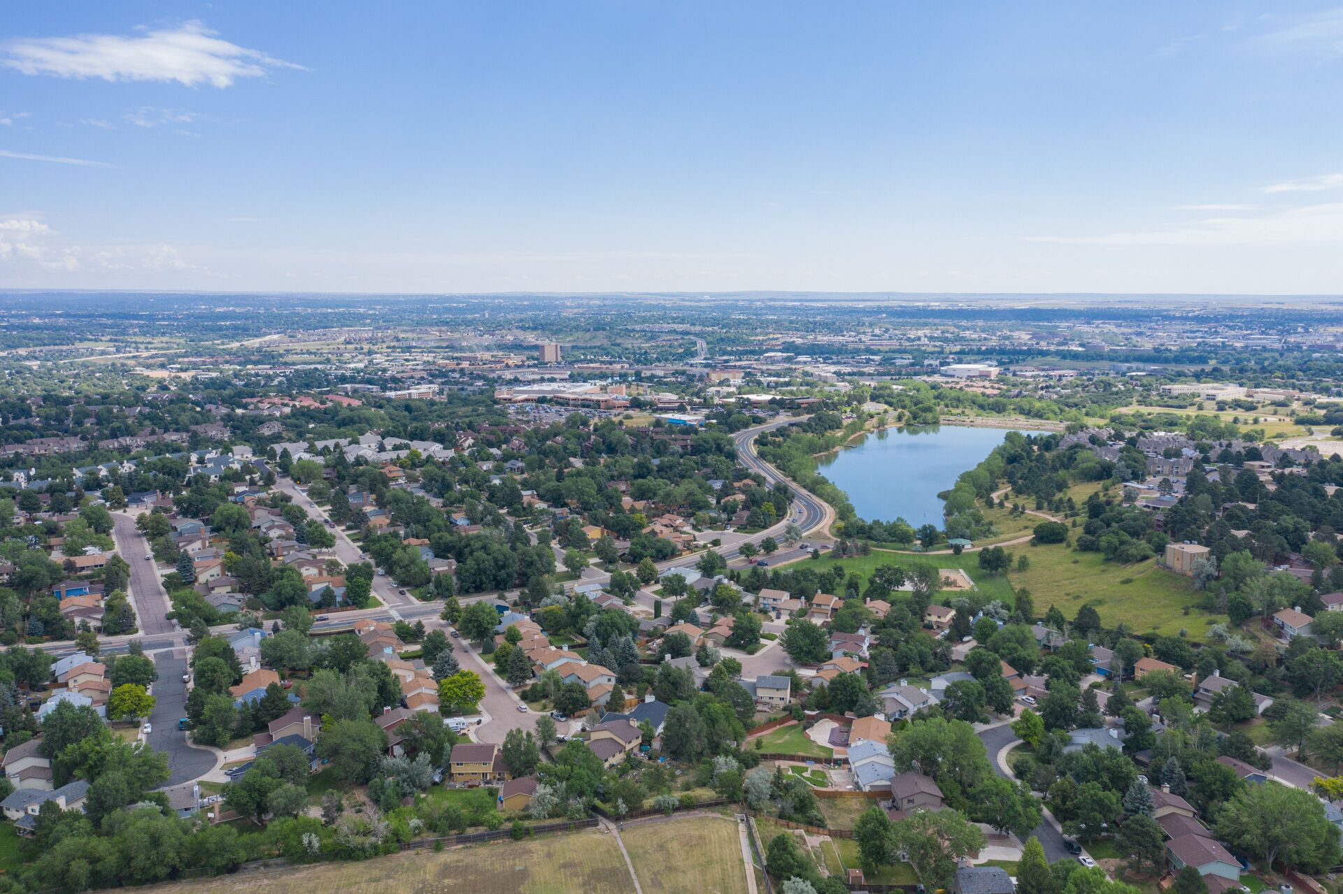 An aerial view of a residential area with houses, roads, and a lake.