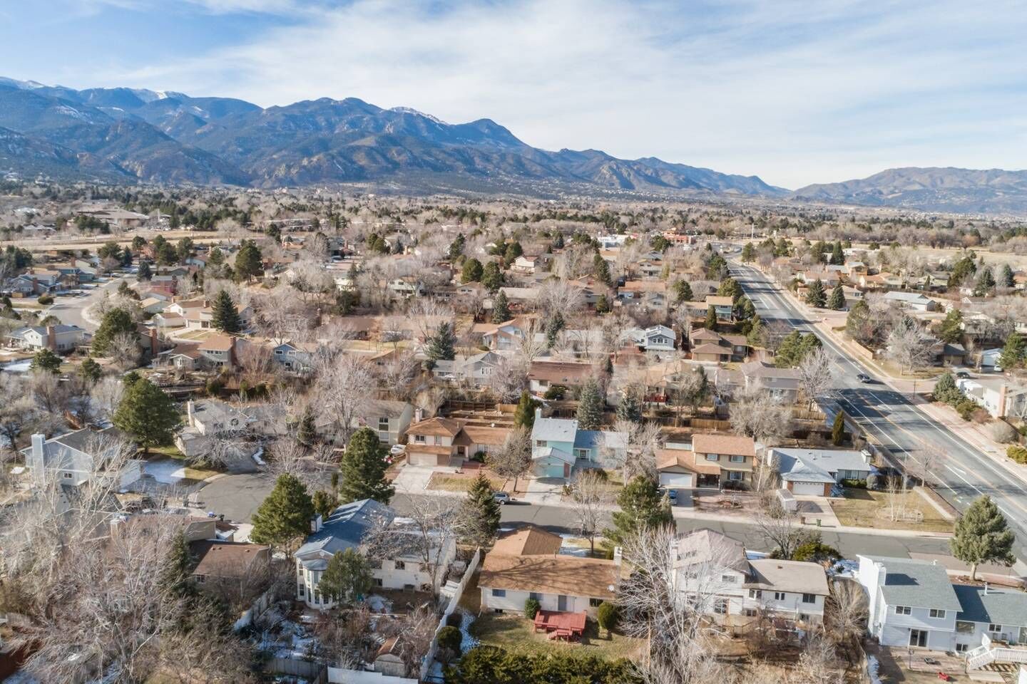 A residential area with houses, roads, and mountains in the background.