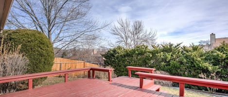 A wooden deck with red railings, surrounded by trees and a wooden fence.